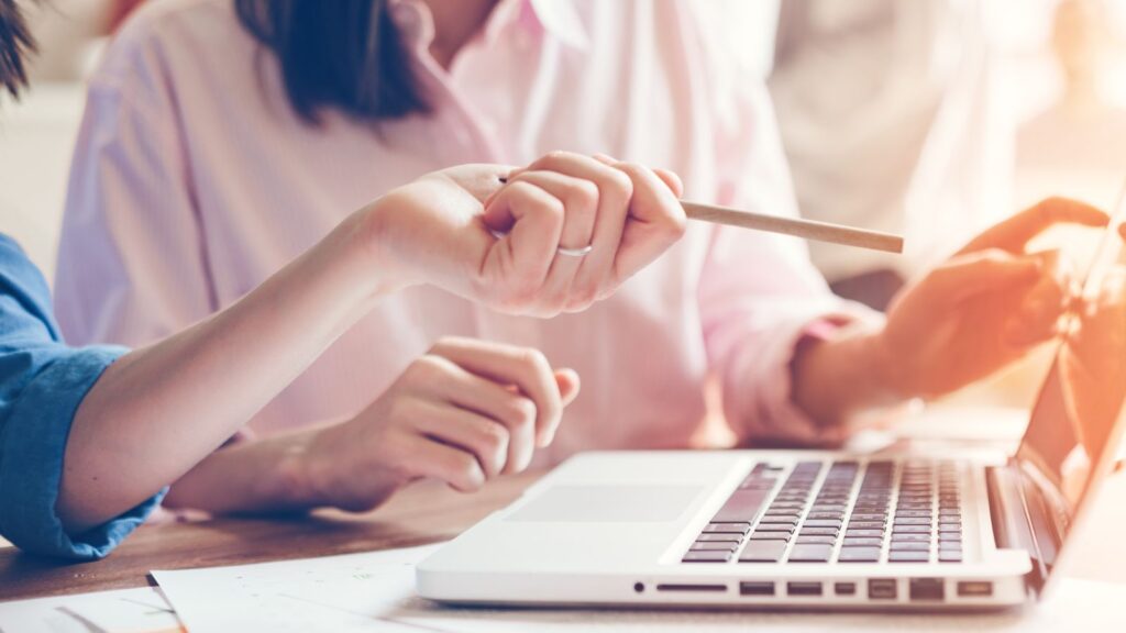 Zwei Personen arbeiten gemeinsam an einem Laptop und tauschen Ideen aus.