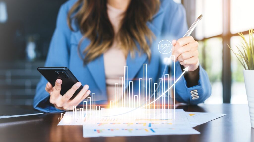 Geschäftsfrau, die ein Smartphone nutzt, um ein Geschäftsdokument mit einem Diagramm zu überprüfen.